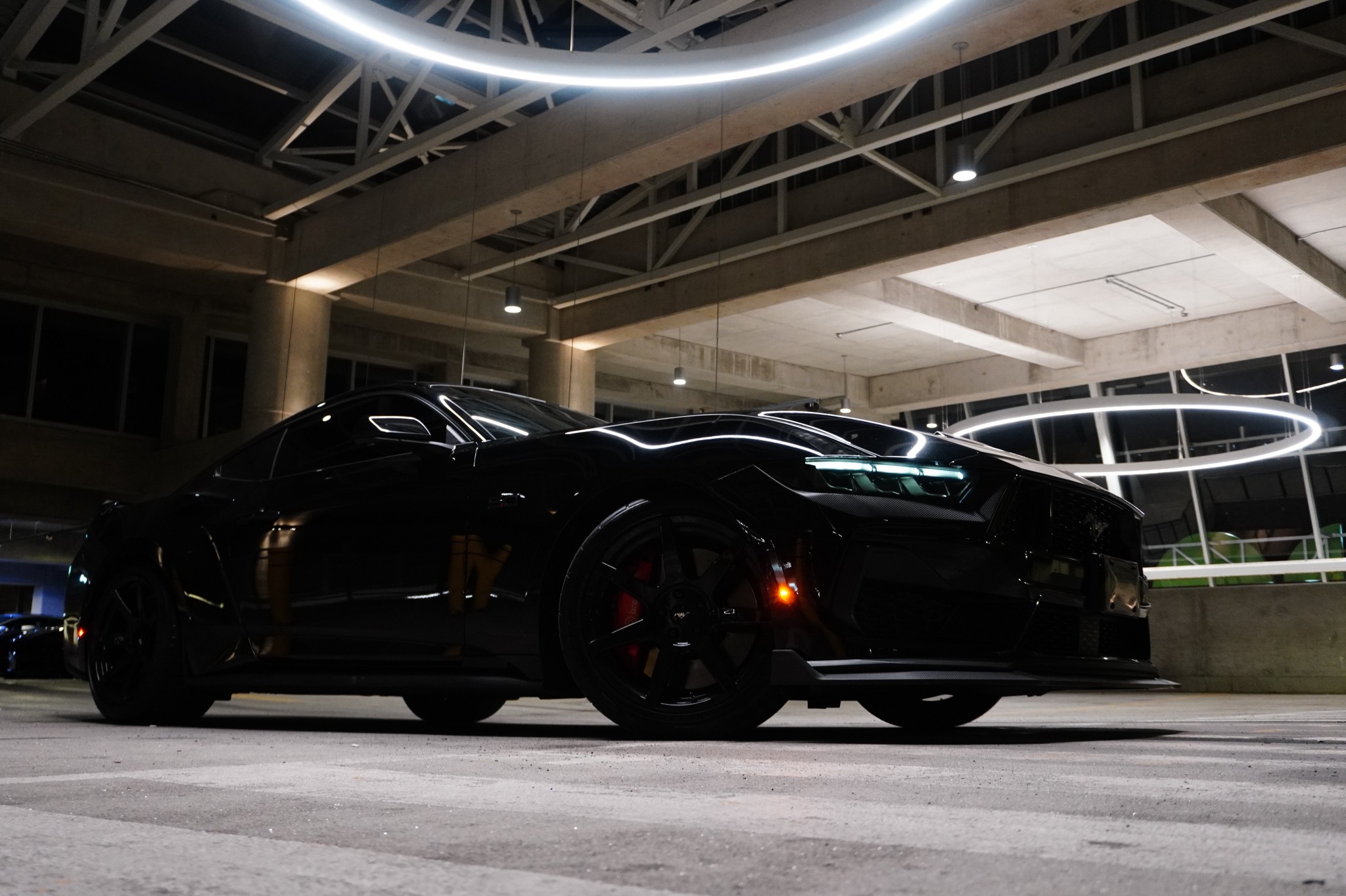 Julian Tiqui’s black Mustang GT beneath circular lights in a concrete structure